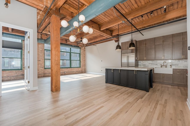 kitchen featuring a sink, baseboards, light wood-style floors, built in refrigerator, and wood ceiling