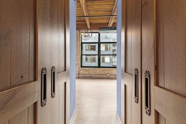 hallway with wooden ceiling, a notable chandelier, wood finished floors, and beamed ceiling