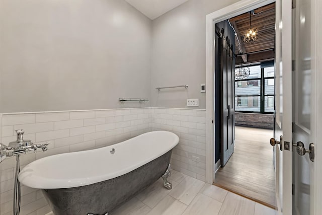 bathroom with tile walls, a wainscoted wall, and a freestanding bath