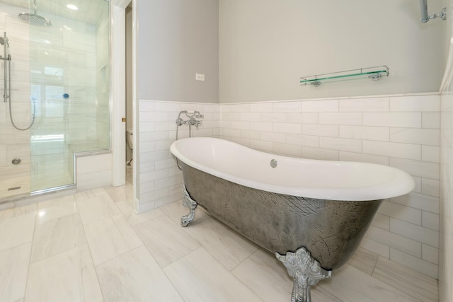 full bath with tile walls, toilet, a freestanding tub, and a tile shower