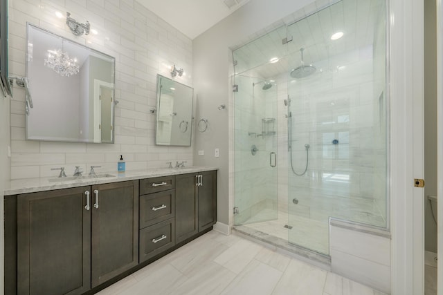 bathroom featuring a notable chandelier, a sink, double vanity, and a stall shower