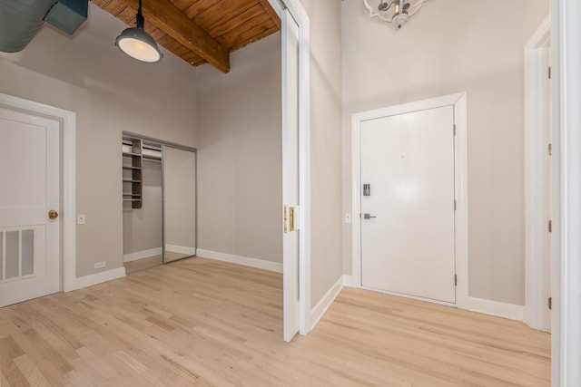 foyer entrance featuring visible vents, light wood finished floors, wood ceiling, and beam ceiling