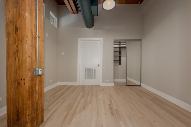 unfurnished bedroom featuring baseboards, a closet, visible vents, and light wood-style flooring