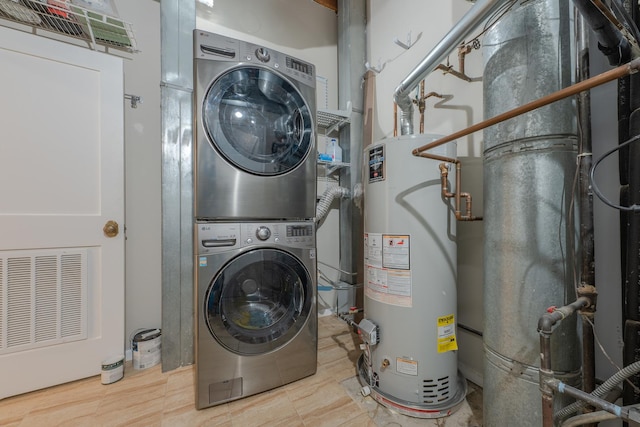 clothes washing area featuring laundry area, visible vents, stacked washer / dryer, and gas water heater