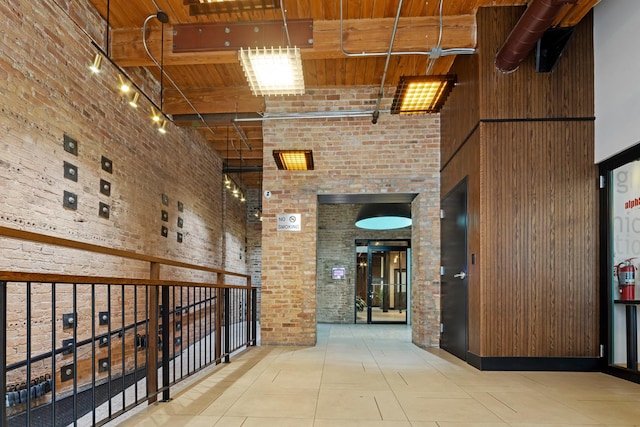 hallway with wood ceiling, brick wall, and a high ceiling