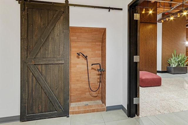full bathroom featuring a tile shower, baseboards, and tile patterned flooring