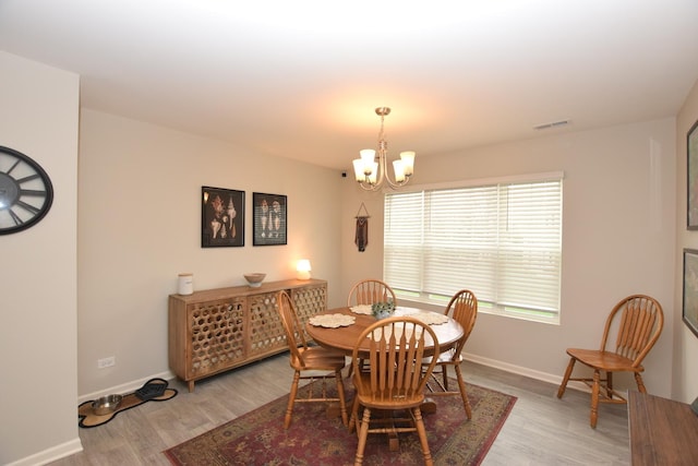dining space with baseboards, a notable chandelier, and light wood-style flooring
