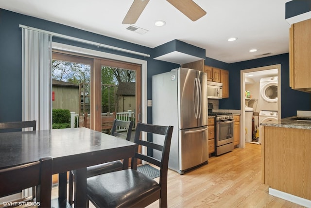 kitchen with appliances with stainless steel finishes, light wood-style floors, a ceiling fan, visible vents, and stacked washer and clothes dryer