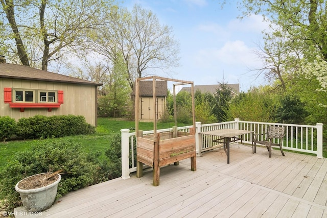 wooden terrace with outdoor dining area, an outdoor structure, and a storage unit