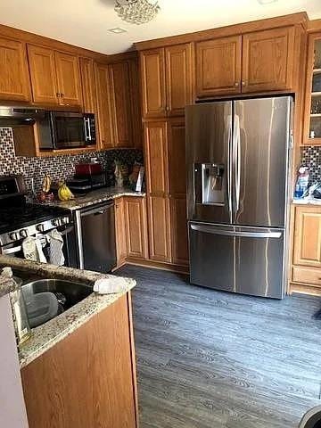 791 Overland Ct, Roselle, IL 60172 - kitchen featuring glass insert cabinets, brown cabinets, light stone counters, backsplash, and stainless steel appliances