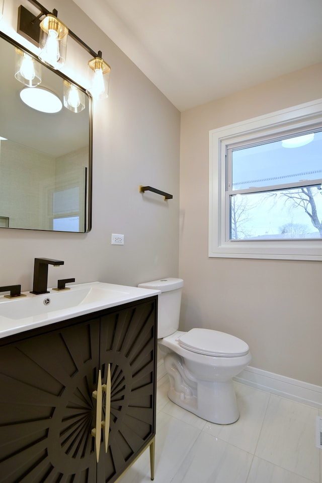 half bath featuring toilet, vanity, and baseboards