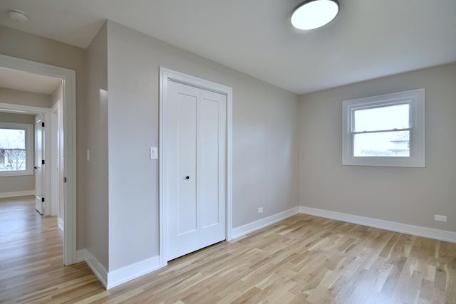 unfurnished bedroom featuring baseboards, a closet, and light wood-style flooring