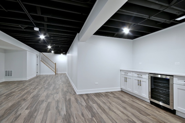 finished basement featuring beverage cooler, visible vents, baseboards, and light wood-style floors
