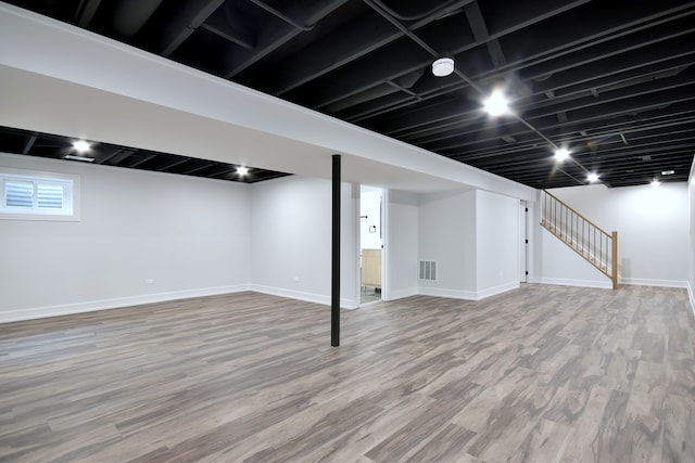 basement featuring stairway, visible vents, wood finished floors, and baseboards