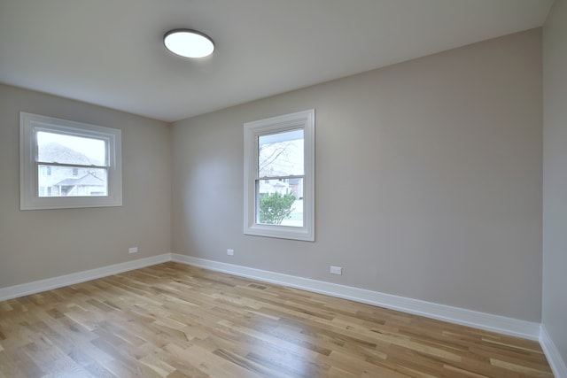 spare room with light wood-style floors, visible vents, and baseboards