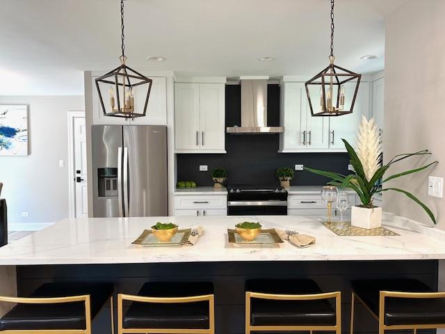 kitchen featuring wall chimney range hood, stainless steel fridge with ice dispenser, white cabinetry, and black / electric stove