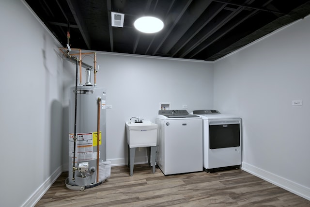 washroom with independent washer and dryer, visible vents, light wood-style floors, water heater, and laundry area