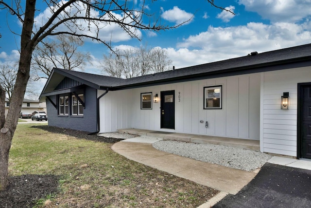 view of front of home with a front yard, board and batten siding, and brick siding