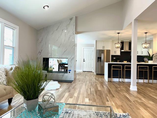 living room featuring light wood-style flooring, baseboards, and an accent wall