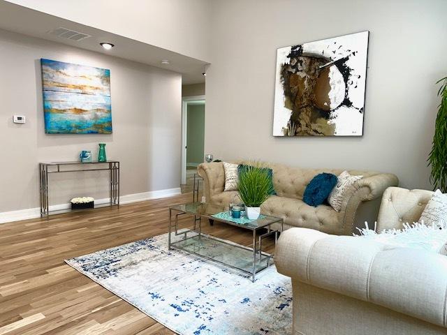 living area with baseboards, wood finished floors, and visible vents