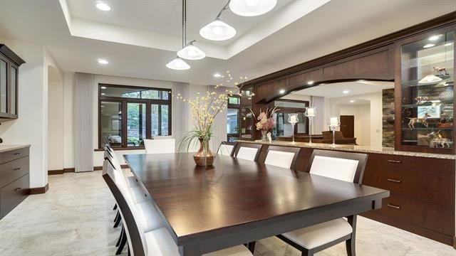 dining room with arched walkways, a tray ceiling, and recessed lighting