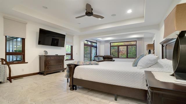 bedroom with arched walkways, a raised ceiling, visible vents, and baseboards