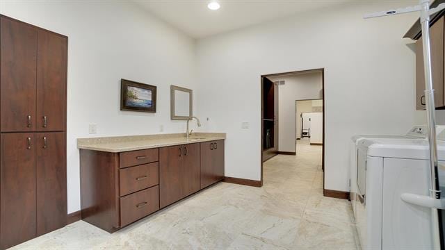 clothes washing area featuring recessed lighting, a sink, baseboards, separate washer and dryer, and cabinet space