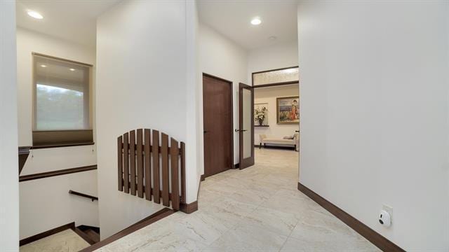 hallway featuring marble finish floor, baseboards, an upstairs landing, and recessed lighting