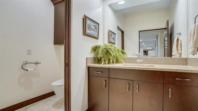 bathroom with baseboards, vanity, and toilet