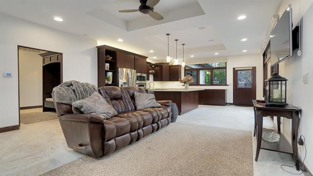 living room featuring light carpet, a ceiling fan, a tray ceiling, and recessed lighting