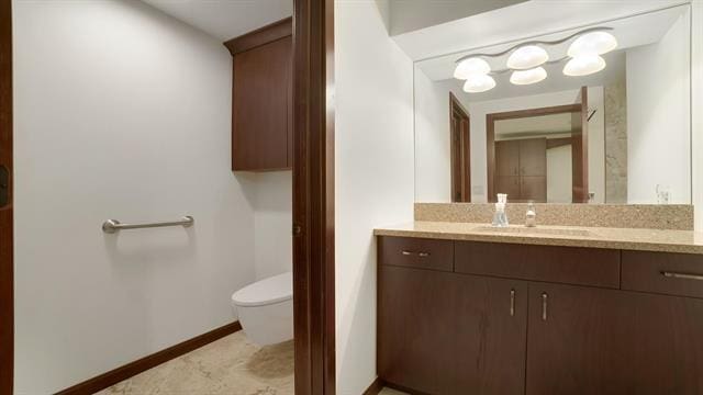 bathroom with baseboards, vanity, and toilet