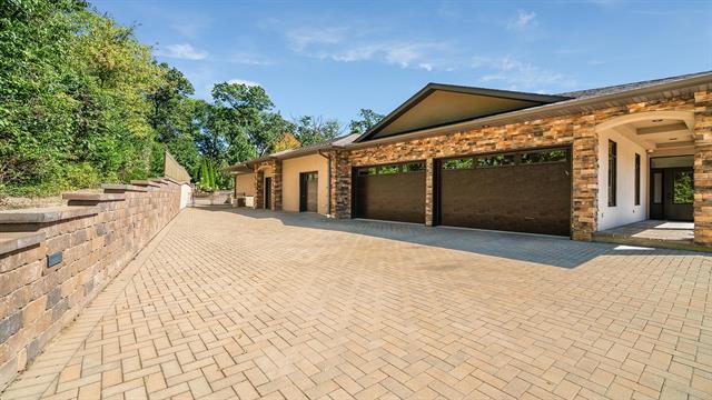 view of side of home featuring an attached garage and decorative driveway