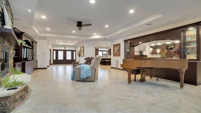 living room with recessed lighting, a raised ceiling, marble finish floor, and ceiling fan