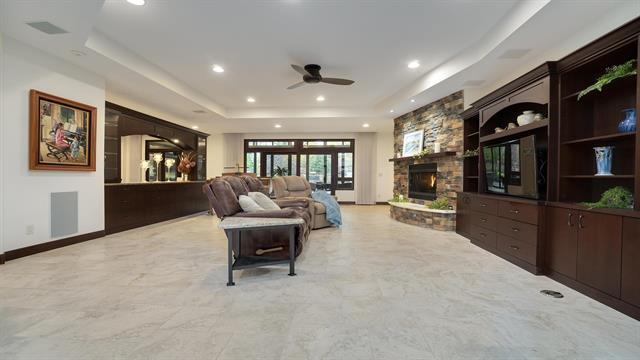 living room featuring a ceiling fan, marble finish floor, a fireplace, a raised ceiling, and recessed lighting