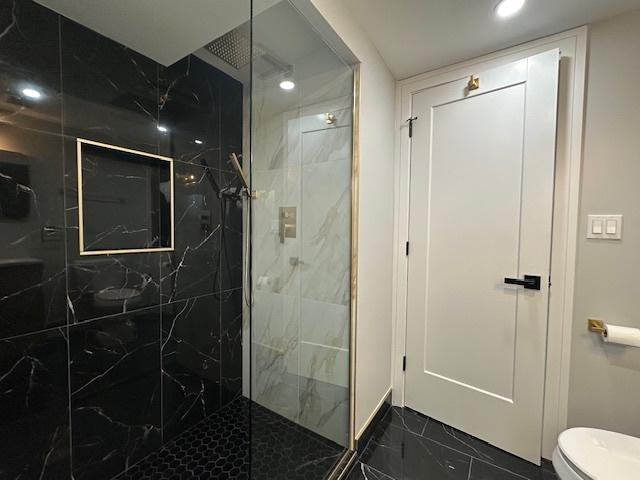 bathroom with marble finish floor, toilet, a marble finish shower, and recessed lighting