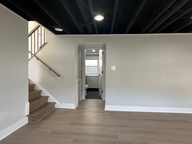 interior space with baseboards, wood finished floors, and stairway