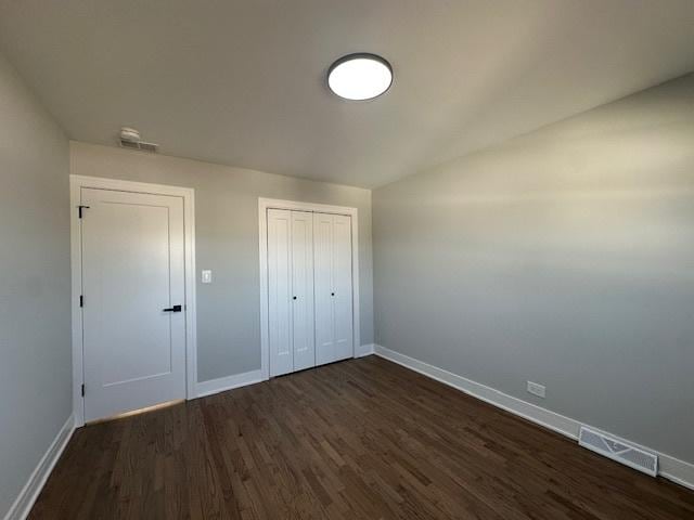 unfurnished bedroom with baseboards, dark wood-type flooring, and visible vents