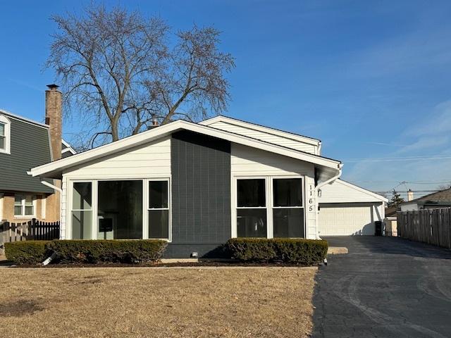 view of front of home with a garage, fence, and aphalt driveway