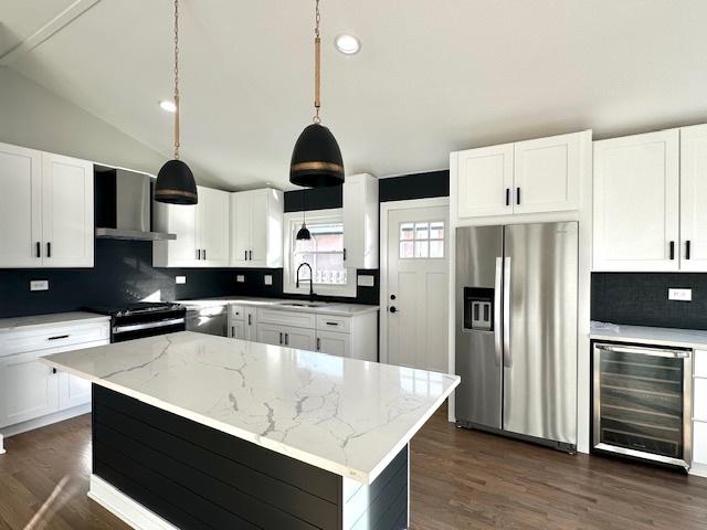 kitchen featuring a sink, decorative backsplash, beverage cooler, stainless steel appliances, and wall chimney exhaust hood
