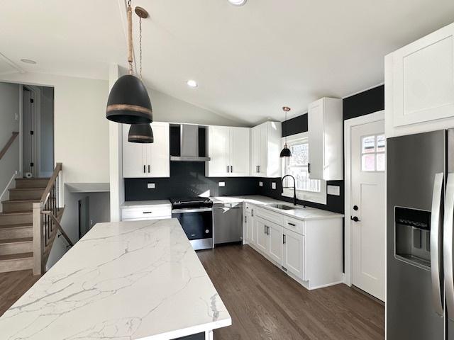 kitchen featuring light stone counters, appliances with stainless steel finishes, a sink, and dark wood-type flooring