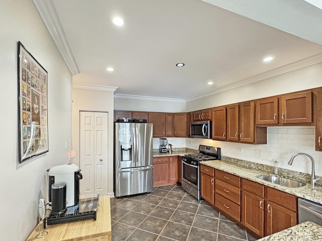 kitchen featuring backsplash, crown molding, appliances with stainless steel finishes, light stone countertops, and a sink