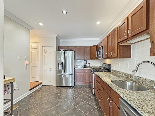 kitchen with dark tile patterned floors, decorative backsplash, light stone countertops, a sink, and stainless steel appliances
