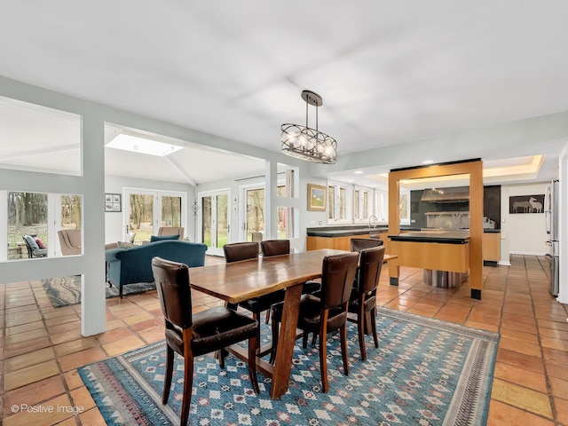 dining space featuring vaulted ceiling with skylight and light tile patterned floors