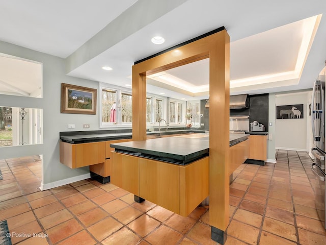 interior space with dark countertops, freestanding refrigerator, baseboards, recessed lighting, and a raised ceiling
