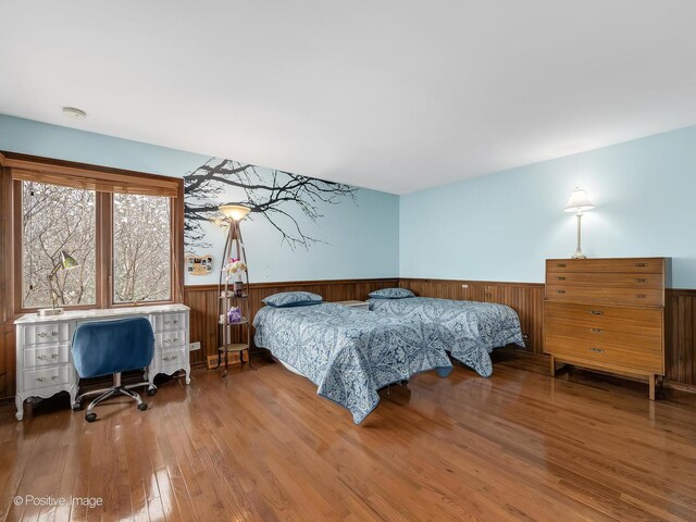 bedroom with wood finished floors and wainscoting