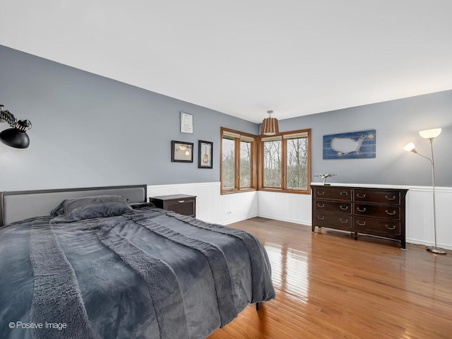 bedroom featuring wainscoting and wood finished floors