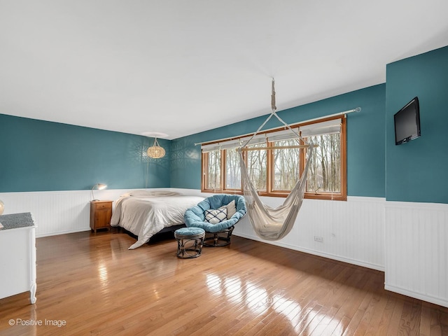 bedroom with wainscoting and hardwood / wood-style floors