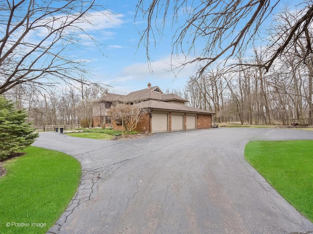 view of side of property featuring an attached garage, aphalt driveway, and brick siding