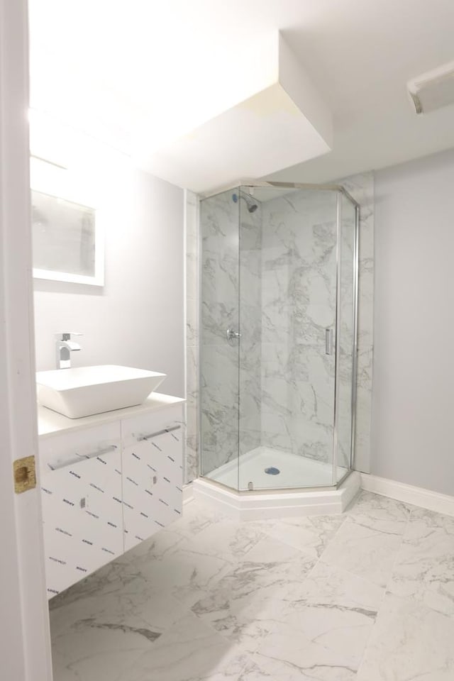 bathroom featuring marble finish floor, baseboards, vanity, and a marble finish shower