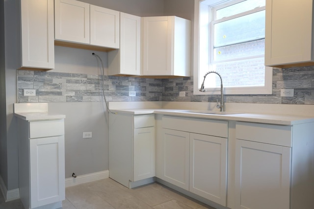 kitchen featuring light countertops, tasteful backsplash, white cabinetry, and a sink